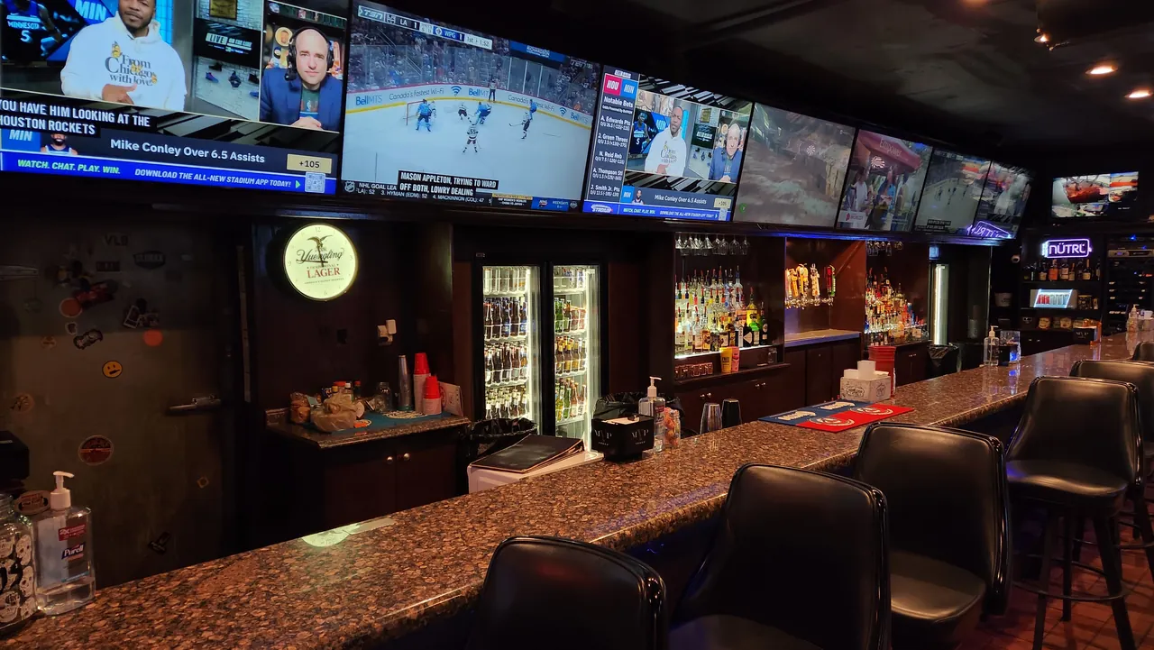 Bar seating beneath a row of sports televisions at Sparks